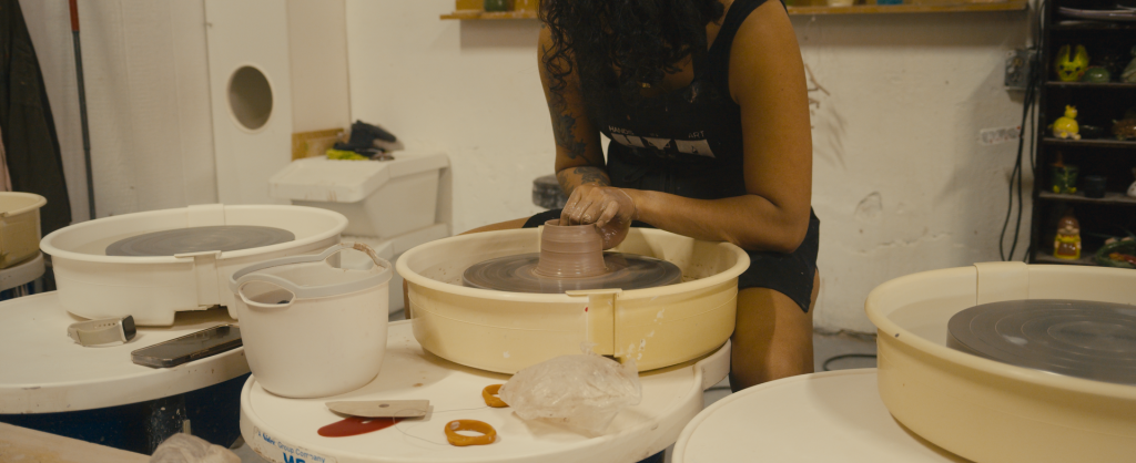 A person at the pottery wheel trying to make a piece.