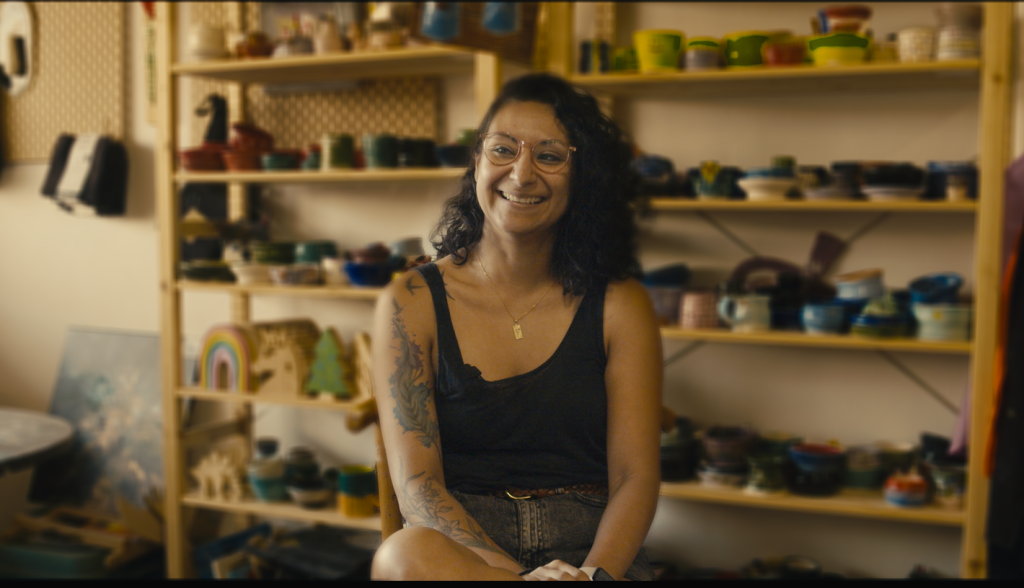 A person sitting down at Hands in Art Studio in front of several ceramic pieces.