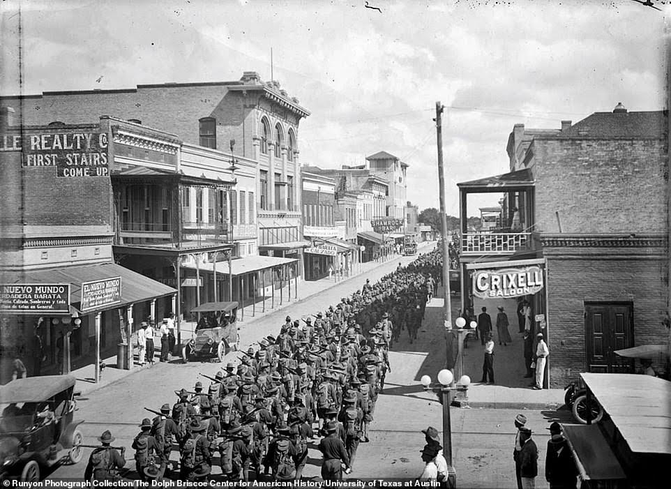 Historical black and white photo showing thousands of National Guardsmen marching in the streets of Brownsville, Texas.
