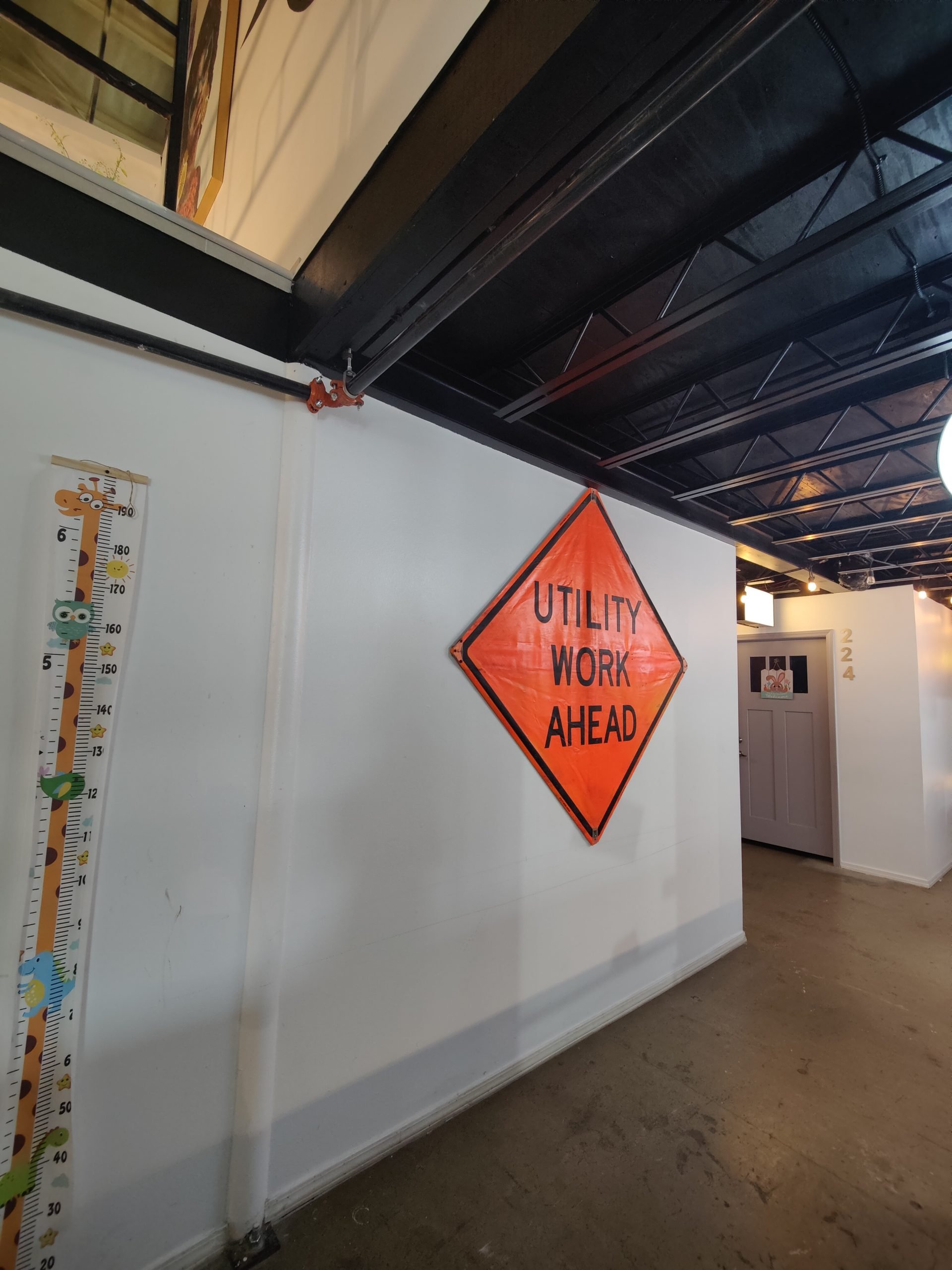 An indoor flea market currently under construction. The shops are covered by blue tarps with string lights throughout the ceiling.