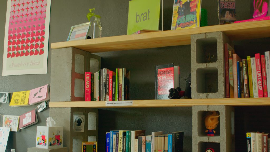 Bookshelves made out of slabs of wood held by bricks displaying a variety of books. Vinyls are also displayed at the top of the shelves inside Ante Books.