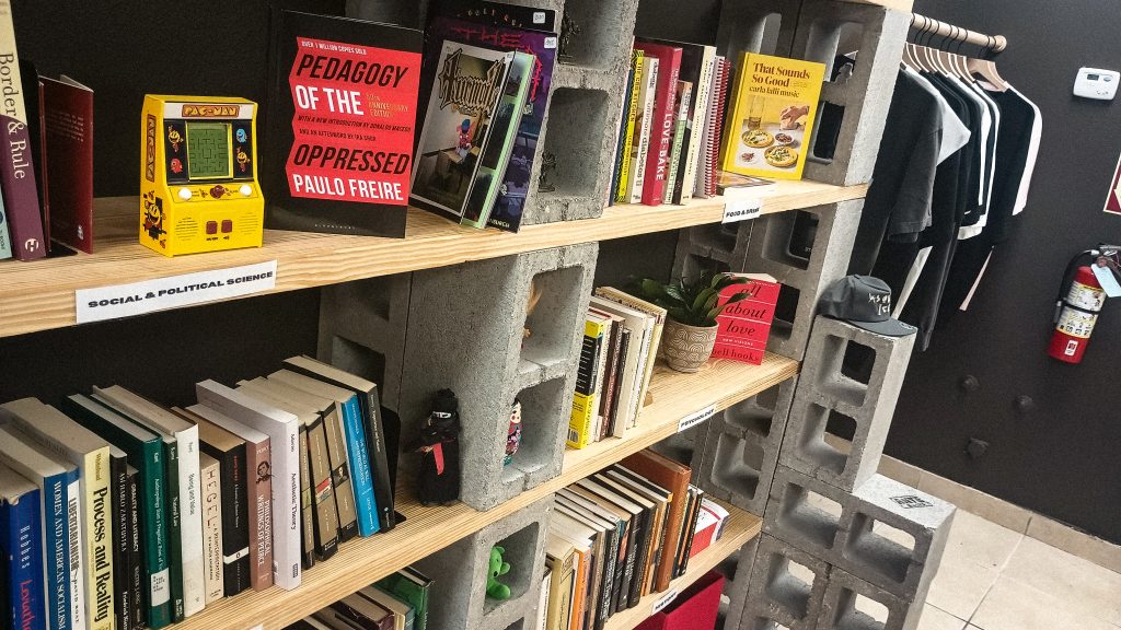 Bookshelves made out of slabs of wood held by bricks displaying a variety of books in McAllen, TX.
