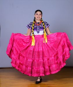 lthough Tati identifies as non-binary, they use Folklórico to express their femininity and choose vibrant colors in their costumes, such as this bright pink dress from the state of Oaxaca, Mexico.