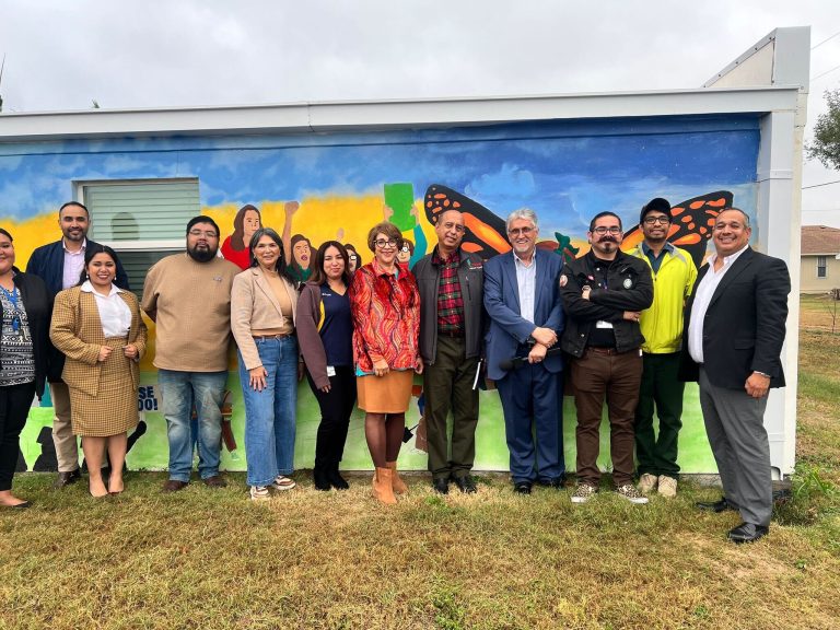 A group of people posing in front of a colorful mural.