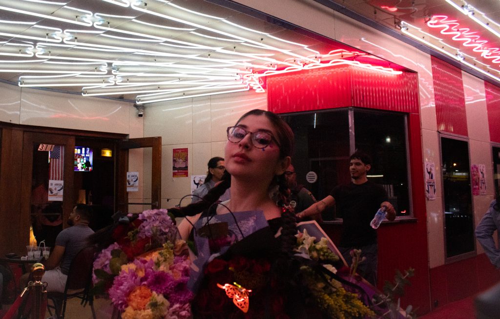 A young woman poses for a photo holding flower bouquets.