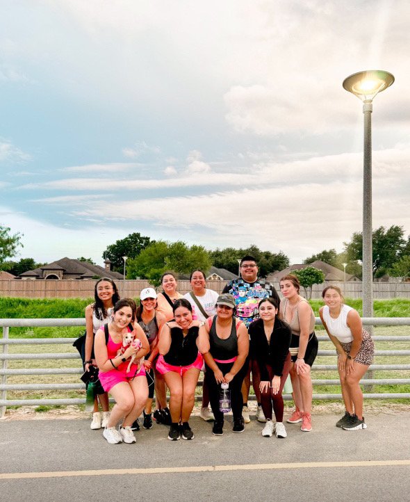A group of people and a puppy, in athleisure wear, posing after a walk.
