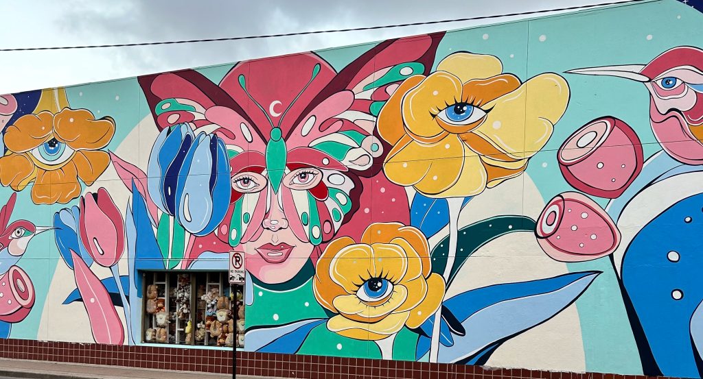A colorful mural filled with flowers, butterflies and hummingbirds.