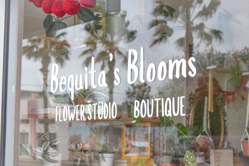 A window with the sign for Bequita’s Blooms.