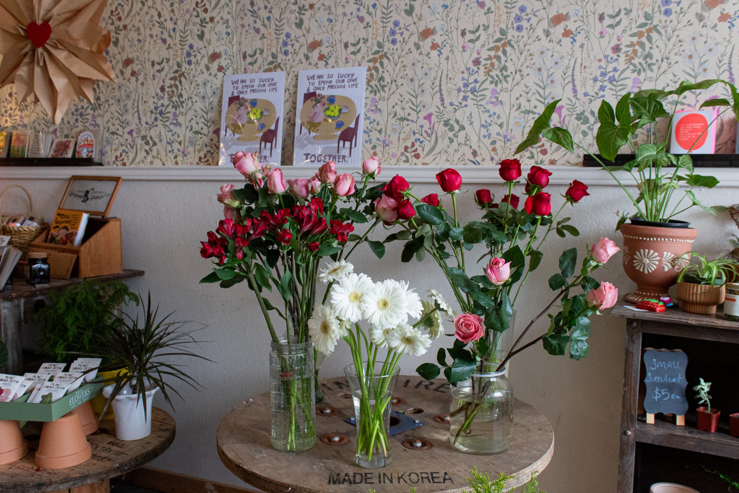 Red and pink roses on a makeshift wooden table at Bequita’s Blooms.