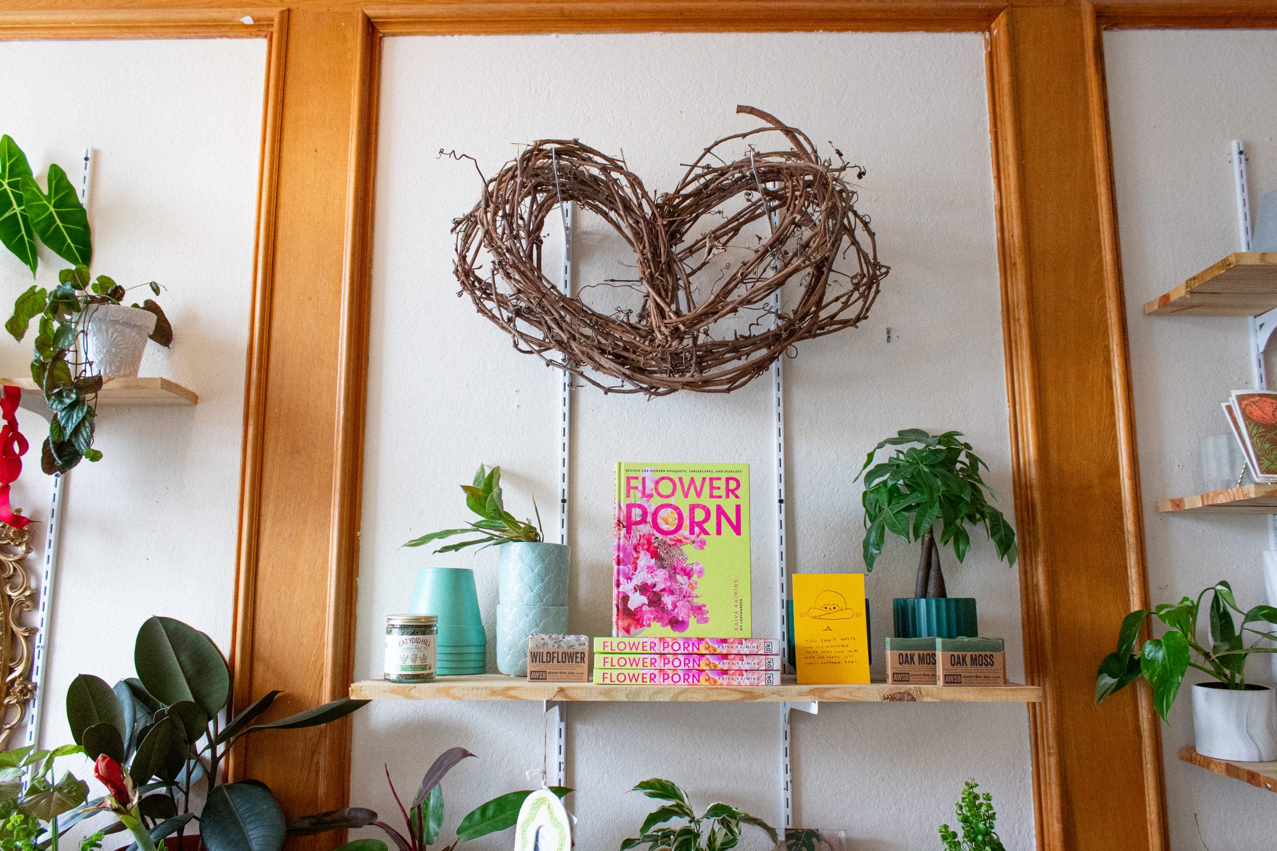 A heart-shaped branch arrangement hangs above some books and soaps.
