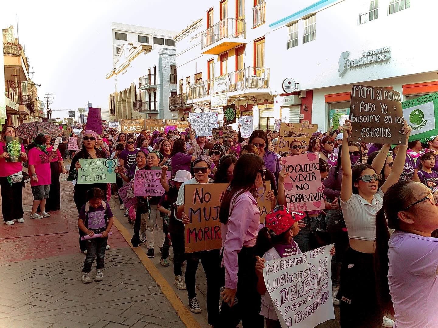 Women march the streets of Matamoros, holding signs and banners.