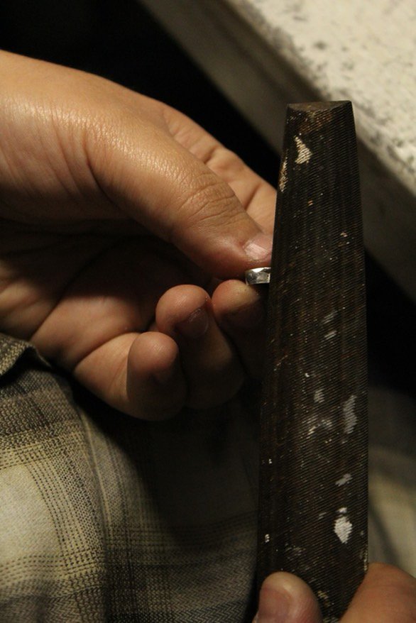 A jeweler filing a ring.