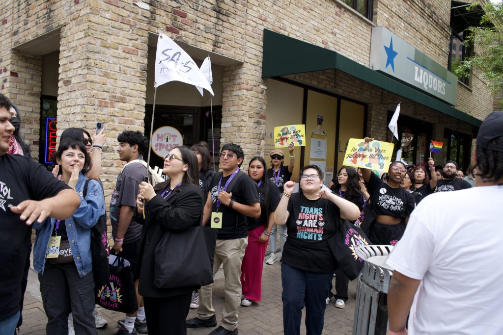 Multiple people marching and holding flags.