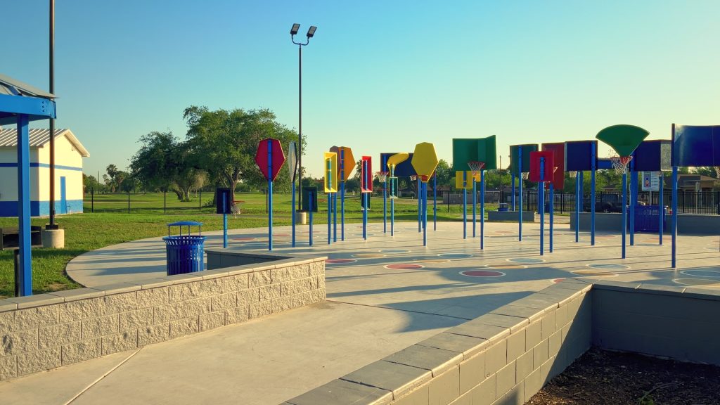 A wide shot of colorful basketball courts of various sizes at a park.