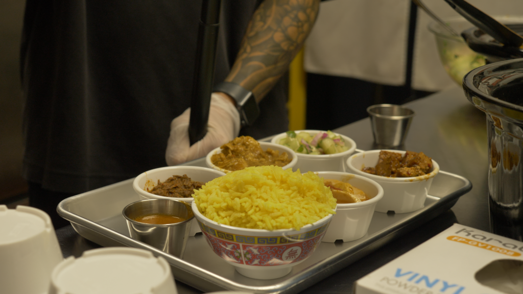 A meal being prepared in a kitchen, small bowls with rice, proteins, and cucumber salad.