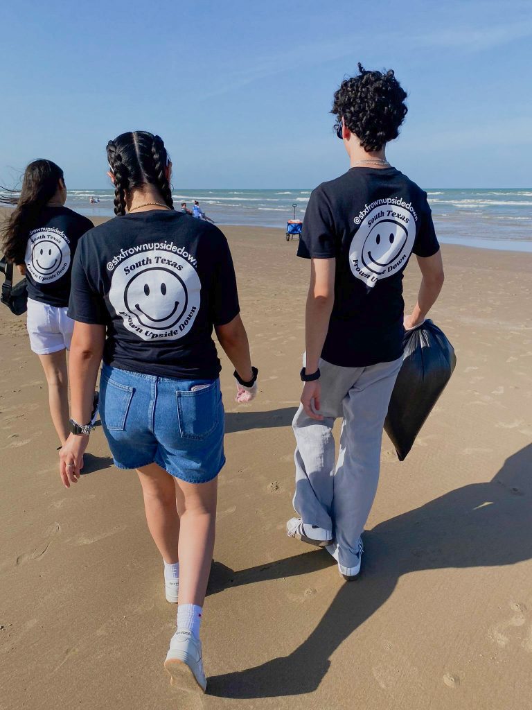Three people walking confidently by the beach shore.