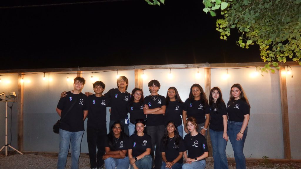 A group standing in front of a white wall as they pose for a photo.