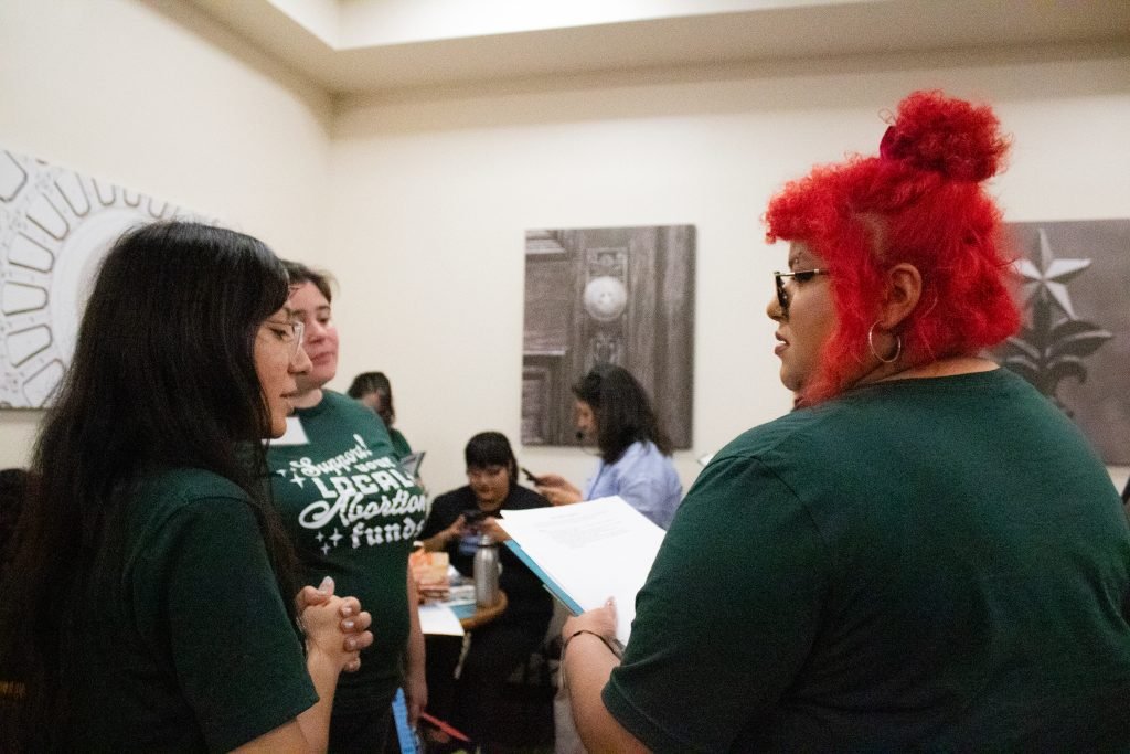 Multiple people in green shirts are having a conversation.