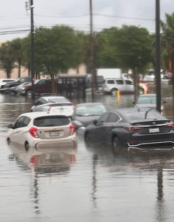Multiple cars flooded in a parking lot.