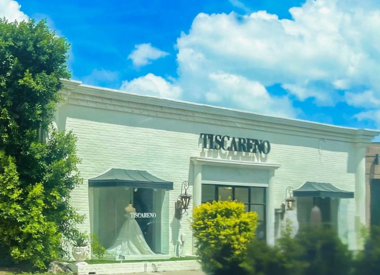 A white brick building with a sign that reads "Tiscareño Bridal" and a wedding dress being showcased in the window.