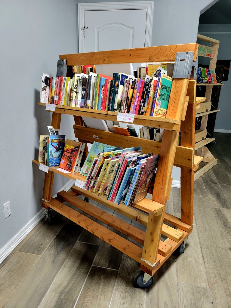 A mobile wooden cart filled with books.