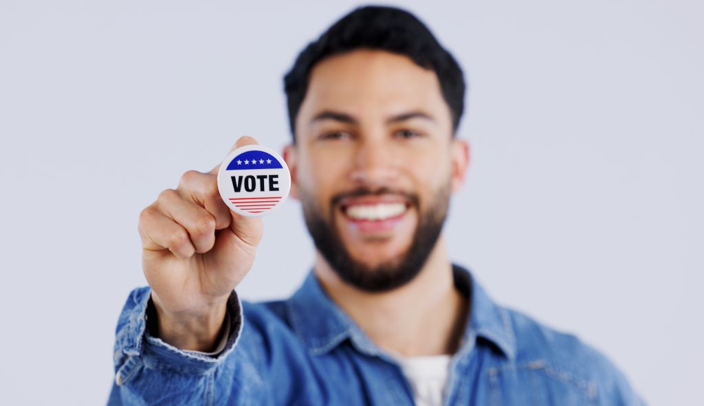 Vote, smile and portrait of man in studio with badge for choice, decision or registration on grey b.