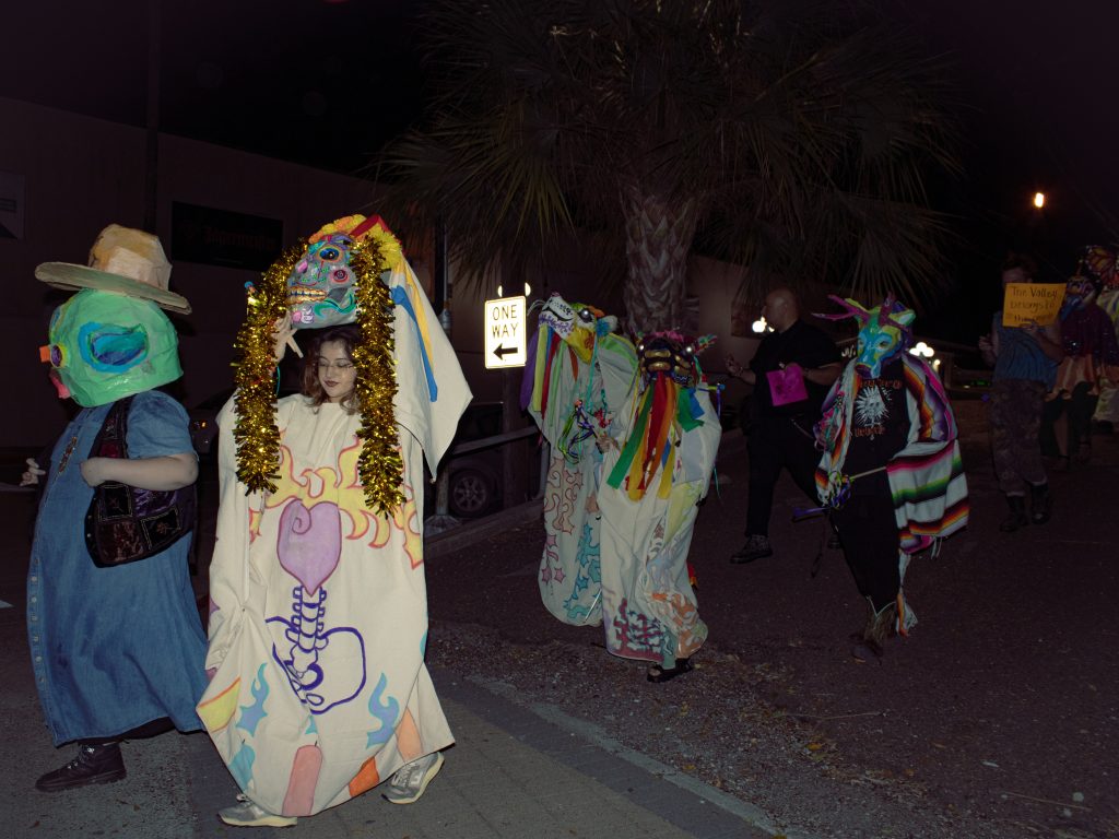 People in masks and costumes walk together in downtown Brownsville.