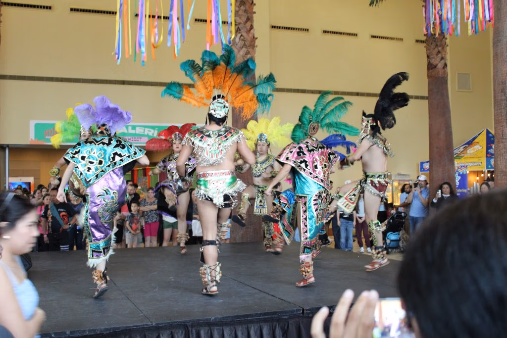 Performers wearing native pre-Hispanic attire dancing.