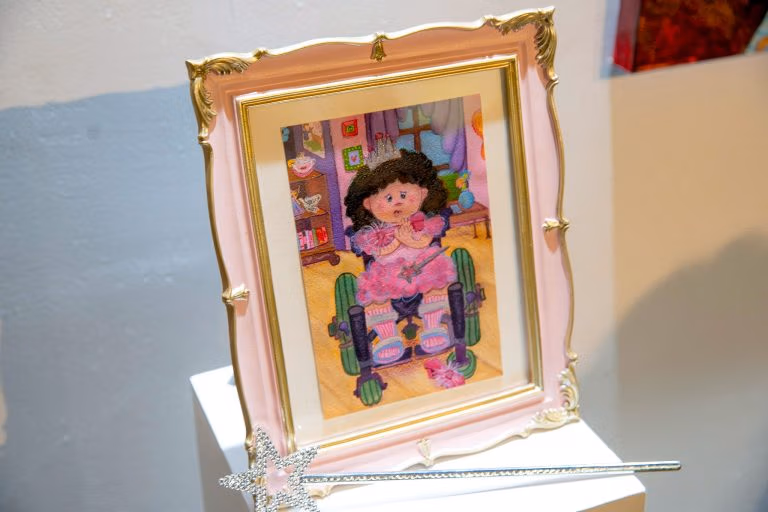 A fancy pink frame featuring a painting of a princess in a wheelchair.