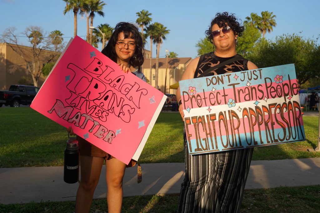 The photo shows two STEP volunteers, Yerb and Azul, proudly displaying signs. Yerb (left) holds one that says: “Black Trans Lives Matter,” and Azul’s (right) states: “Don’t Just Protect Trans People, Fight Our Oppressor.”