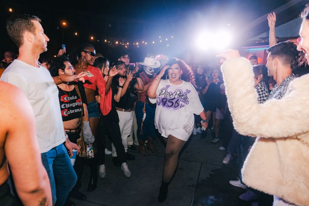 A drag queen walking through a crowd of attendees. 