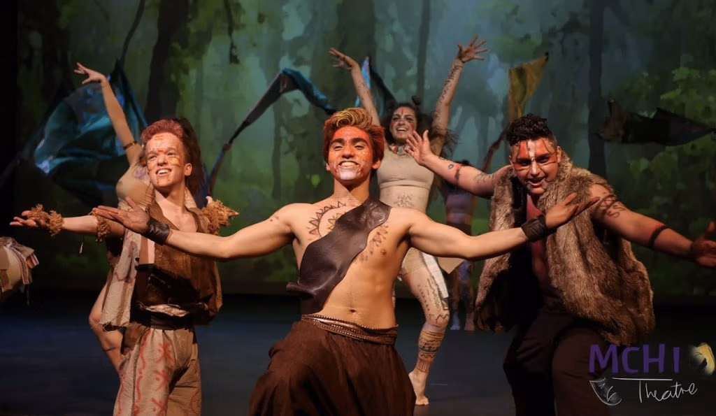 People acting on stage holding out their arms dressed in wilderness clothing.