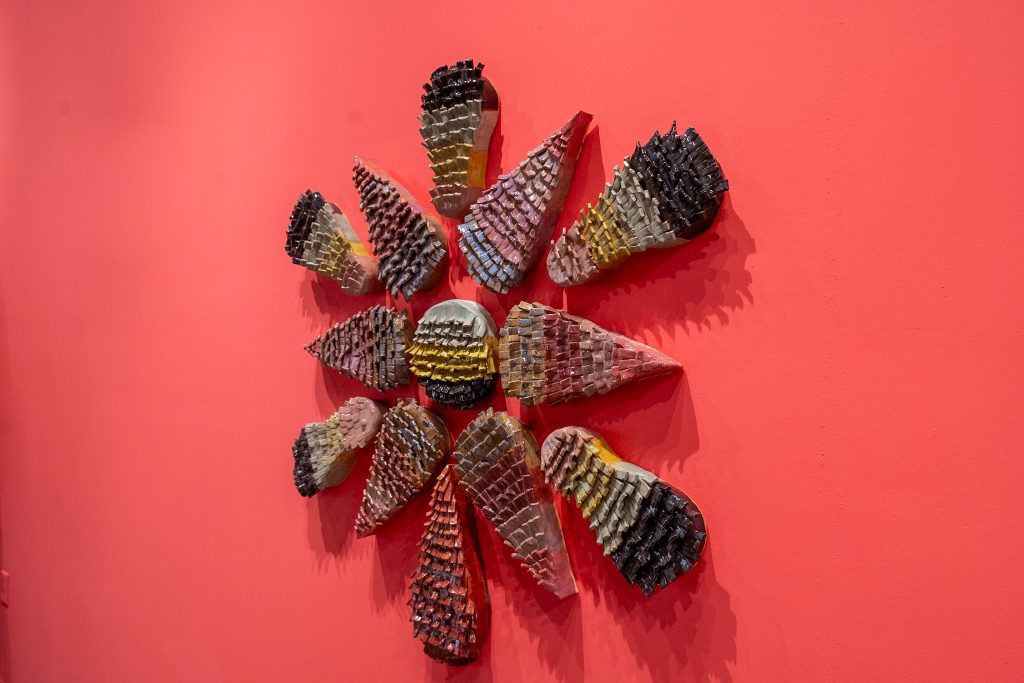 Josuè Ramirez, “Fringe Form,” 2025; fringe-style ceramic piece on display on a bright magenta wall