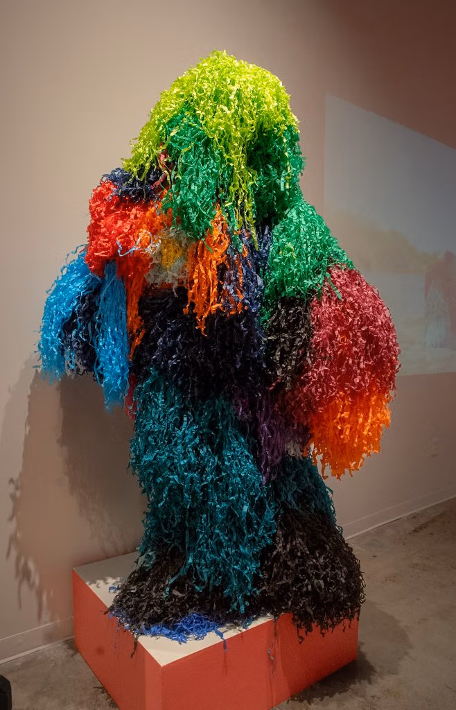 Josuè Ramirez, “Piñata Person: Spill,” 2025; a humanoid pinata person on display in a museum
