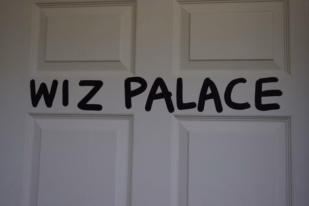 “WIZ PALACE” can be read in black-painted letters on the restroom door.